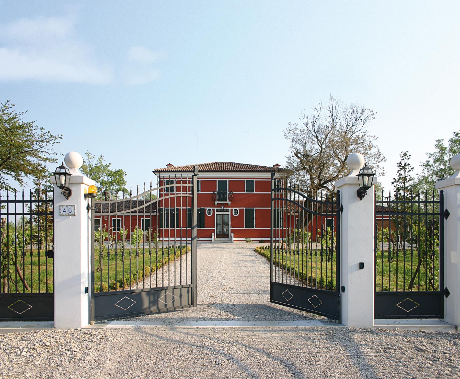 Cancello automatico a due ante davanti a una villa rossa